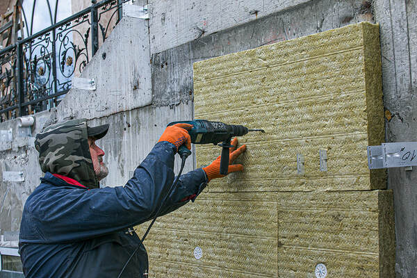 A man drills an insulation sheet into a wall in Hartford, Connecticut.