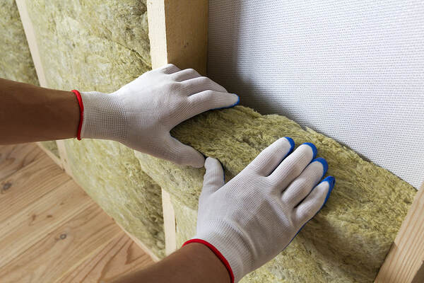 A man was installing Fibreglass insulation in the home walls in Hartford, CT.