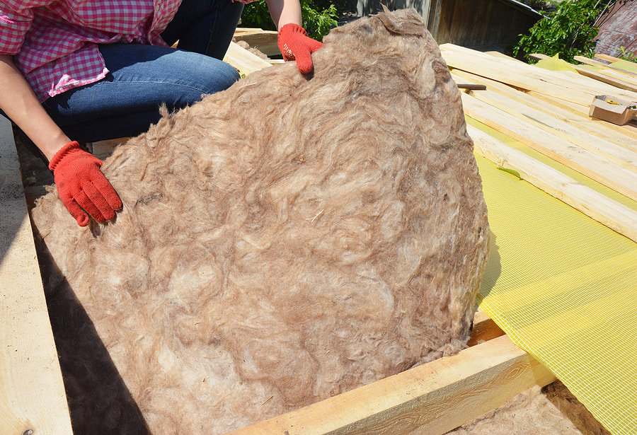 In Hartford, CT, a man insulates a home with fibre wool.